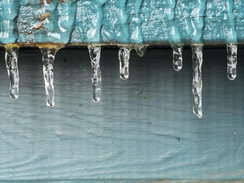 Deck Icicles The aftermath of some freezing rain and temperatures. Small icicles hang in a row from a wooden painted deck rail.